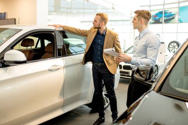 Genç danışman yeni arabanın özellikleri hakkında konuşuyor.