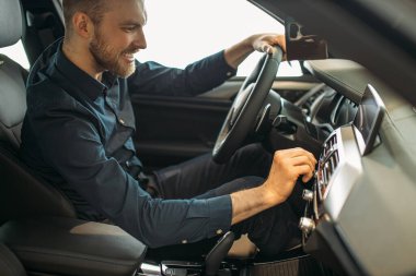 Genç beyaz adam satın almadan önce yeni arabayı inceliyor.