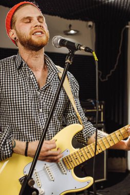 Gitarist aynı anda gitar çalar ve bir şarkı söyler.