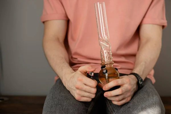 Young man smokes cannabis using bong — Stock Photo, Image