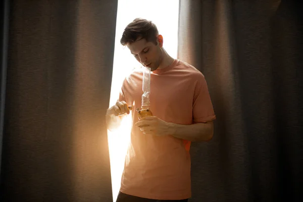 Young man heats bong with a lighter — Stock Photo, Image