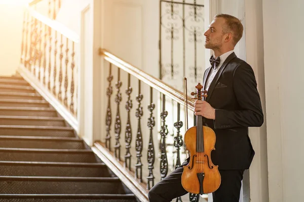 young male holding violin in hands