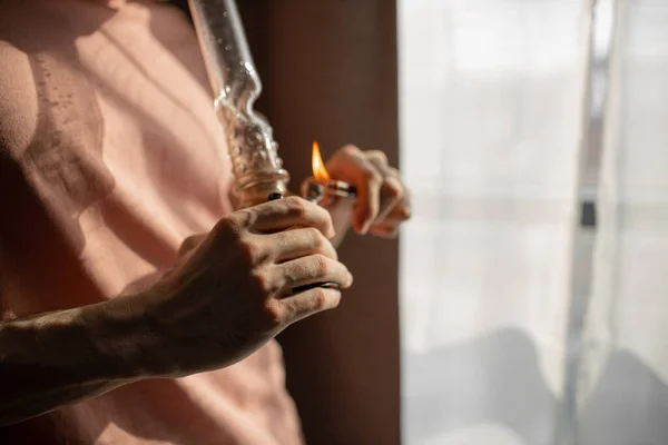 Cropped young man heats bong with a lighter — Stock Photo, Image