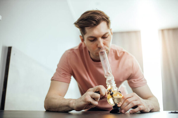 young caucasian man heats bong