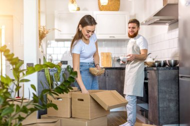 Genç beyaz evli çift evde kutuları boşaltıyor.