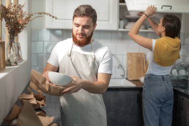Taşınma günü, mutfakta yan yana duran çift, kutuları boşaltıyor.