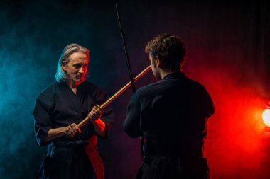 İki Kendo dövüş sanatları dövüşçüsü karanlık uzayda izole bir şekilde siluette dövüşüyor.