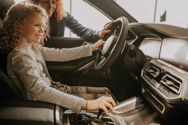 Şirin beyaz çocuk galeride yeni bir arabanın direksiyonunda oturuyor.