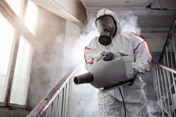 Disinfector with protective antiviral mask, chemical decontamination sprayer bottle indoors — Stock Photo, Image