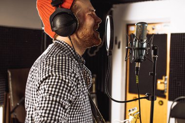 Profesyonel şarkıcı kayıt stüdyosunda şarkı söylüyor.