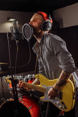 Yetenekli beyaz müzisyen gitar çalıp şarkı söylüyor.