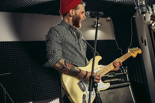 Emocionální zpěvák hrát elektrickou kytaru ve studiu — Stock fotografie