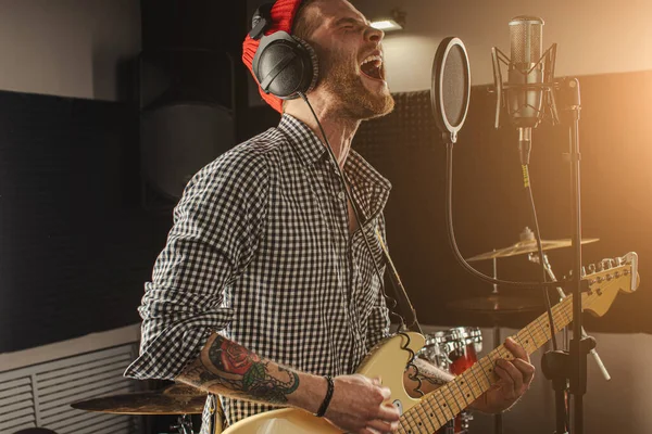 Jonge prachtige muzikant spelen elektrische gitaar en zingen in de studio — Stockfoto