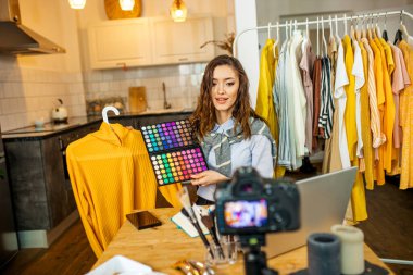 Beyaz bir bayan kıyafetlerini kameraya gösteriyor.