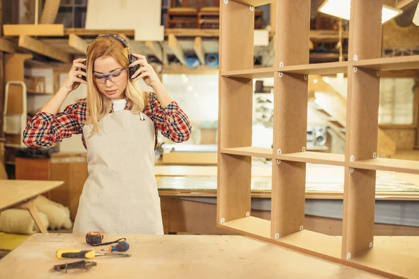 Mujer carpintera usando auriculares durante el trabajo — Foto de Stock