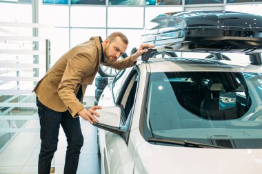 Genç beyaz adam satın almadan önce yeni arabayı inceliyor.