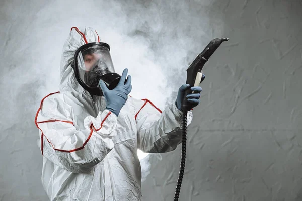 Disinfektor dengan pelindung masker antivirus, penyemprotan dekontaminasi kimia botol di dalam ruangan — Stok Foto