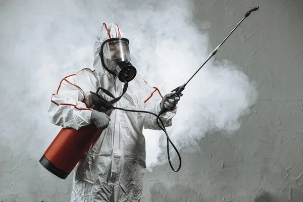 disinfector wearing protective biological suit and gas-mask conduct disinfection