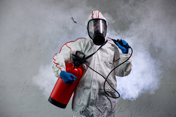мужчина в защитном защитном костюме дезинфицирует общественные изолированные места
