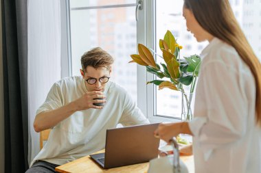 Güzel genç kadın çalışan kocaya çay dolduruyor.