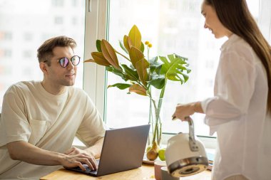 Güzel genç kadın çalışan kocaya çay dolduruyor.