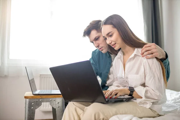 Νεαρό καυκάσιο ζευγάρι εργάζονται μαζί στο σπίτι χρησιμοποιώντας φορητό υπολογιστή — Φωτογραφία Αρχείου