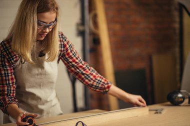 Sevimli kadın marangoz bant hattı kullanıyor.