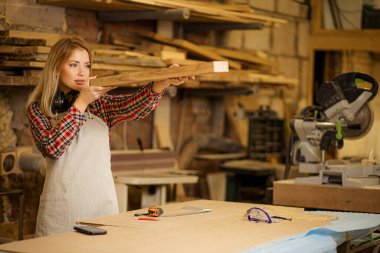 Kafkasyalı genç marangoz kadın odunları kontrol ediyor.