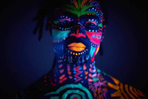 Retrato luminoso del joven en los rayos UV sobre fondo oscuro —  Fotos de Stock