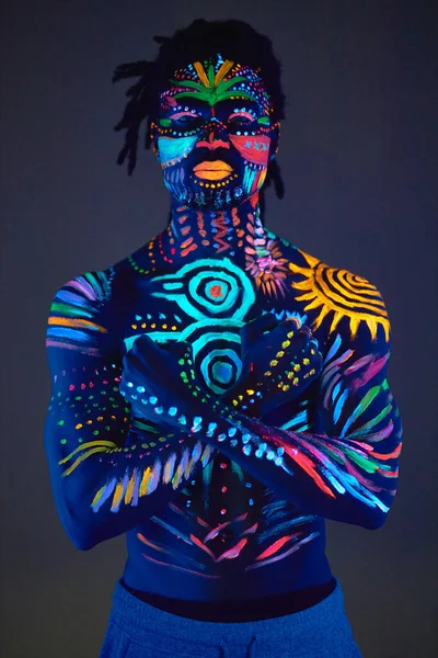 Afričan namalovaný zářivkovou barvou na obličeji a svalnatém trupu bez košile — Stock fotografie