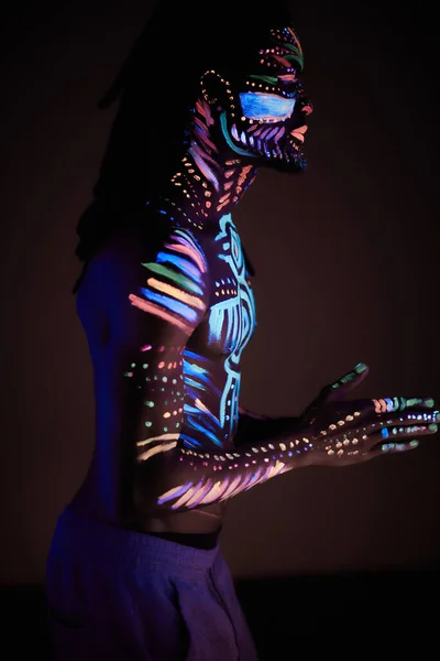 Homem em pintura UV isolado, fundo escuro — Fotografia de Stock
