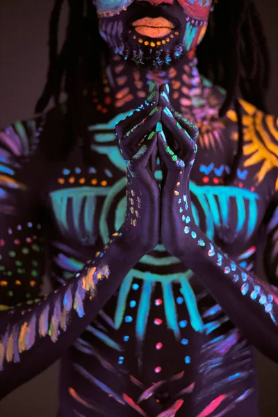 Porträtt av afrikansk man med etniskt mönster, neon makeup i ultraviolett ljus — Stockfoto