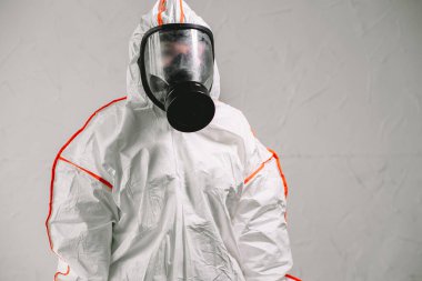 Koruyucu biyolojik giysi ve gaz maskesi takan dezenfektan.