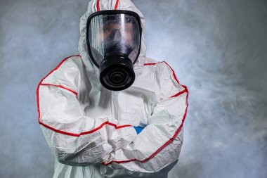 Koruyucu biyolojik giysi ve gaz maskesi takan dezenfektan.