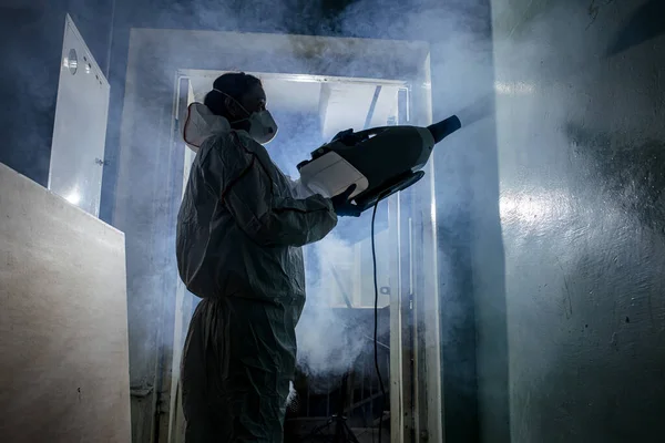 Desinfetor com máscara antiviral protetora, frasco de pulverizador de descontaminação química dentro de casa — Fotografia de Stock