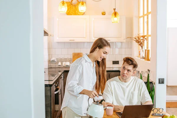 Attractive lady pouring tea to working husband — Stock Photo, Image