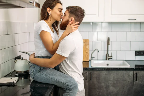 Encantador casal caucasiano beijando na cozinha em casa — Fotografia de Stock