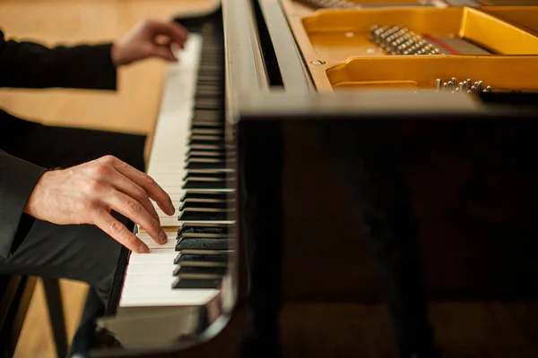 Beskärs oigenkännlig hane spelar piano — Stockfoto