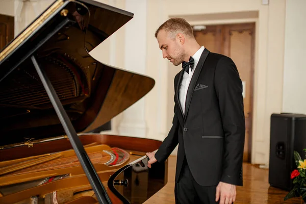 Ung kaukasisk man står bredvid piano — Stockfoto