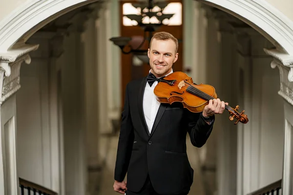 young male holding violin in hands