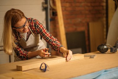 güzel yetenekli marangoz kadın odun parçası ölçüyor.