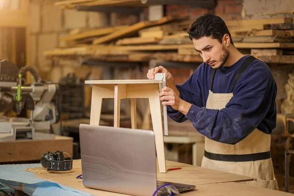 Mladý tesař vyrábět židli v továrně — Stock fotografie