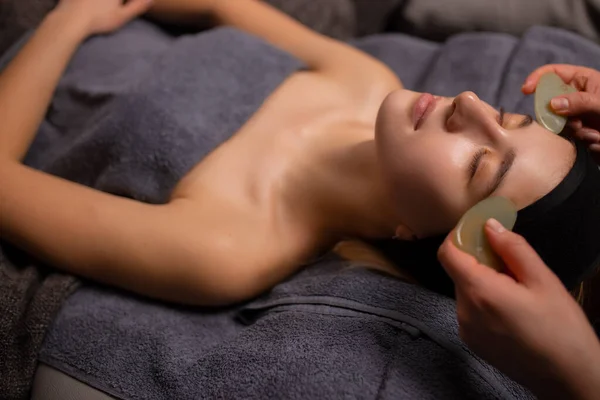 Вид сверху на женщину, получающую массаж лица с использованием косметических средств — стоковое фото
