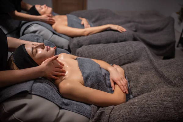 Dos mujeres reciben masaje de cara y cuello en el salón de spa —  Fotos de Stock