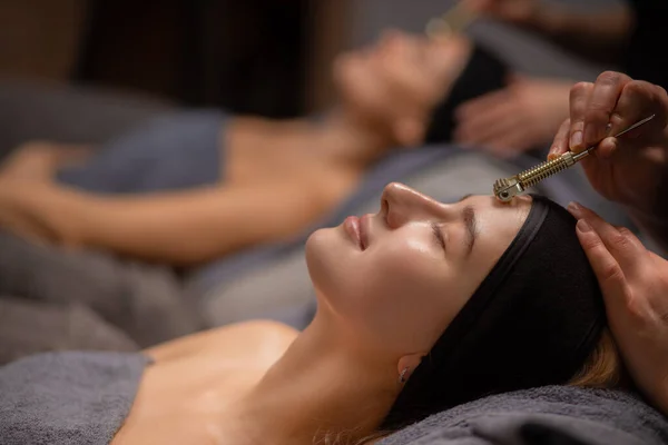 Close-up photo of woman getting massage on forehead with the use of mesotherapy roller — Stock Photo, Image