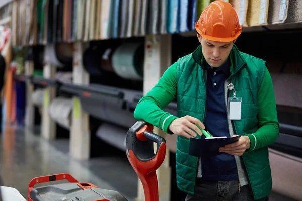 warehouse worker compares product data, reads a document and takes notes