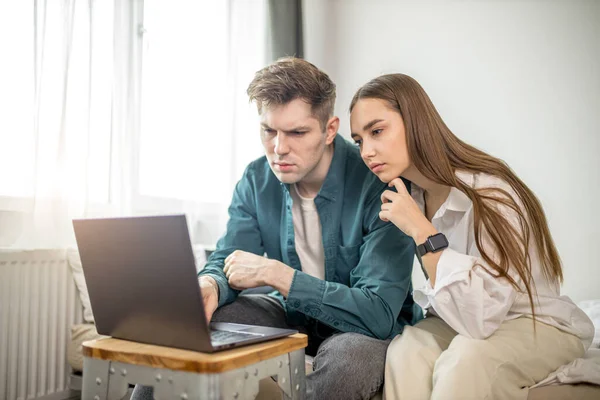 Unga kaukasiska par sitta med laptop hemma — Stockfoto