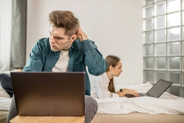 Jovem casal caucasiano trabalham juntos em casa usando laptop — Fotografia de Stock