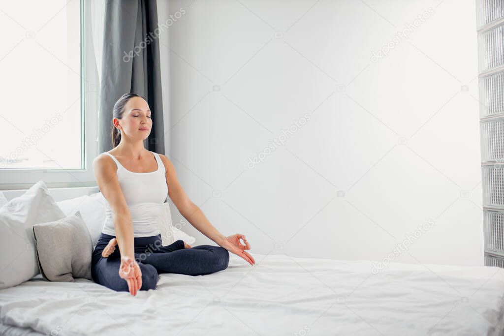 young caucasian lady sit in the lotus pose at home