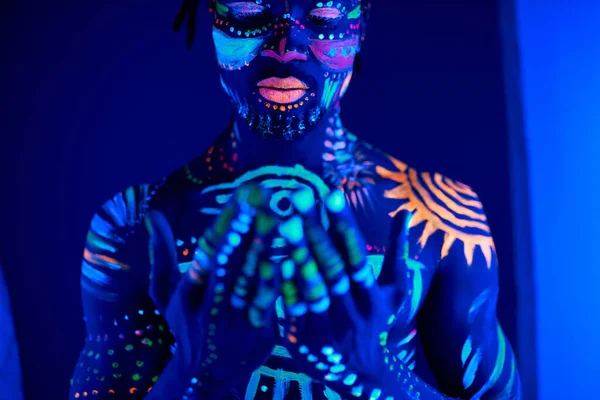 Ruhige afrikanische Mann mit fluoreszierenden Abdrücken auf der Haut beten für das Beste — Stockfoto